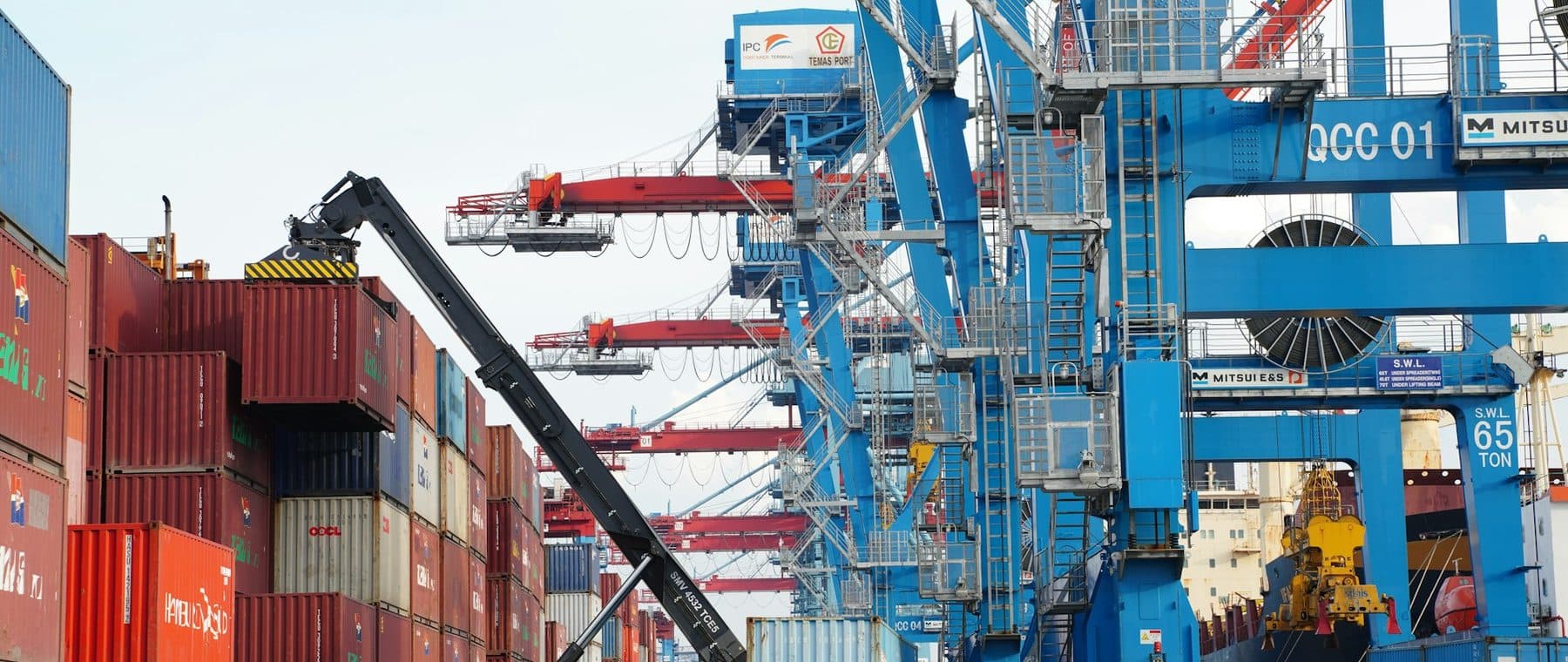 Chariot de manutention et camion entre les piles de conteneurs, sous les portiques