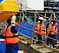 Intervenants en équipement de protection individuelle sur la coupée d'un navire